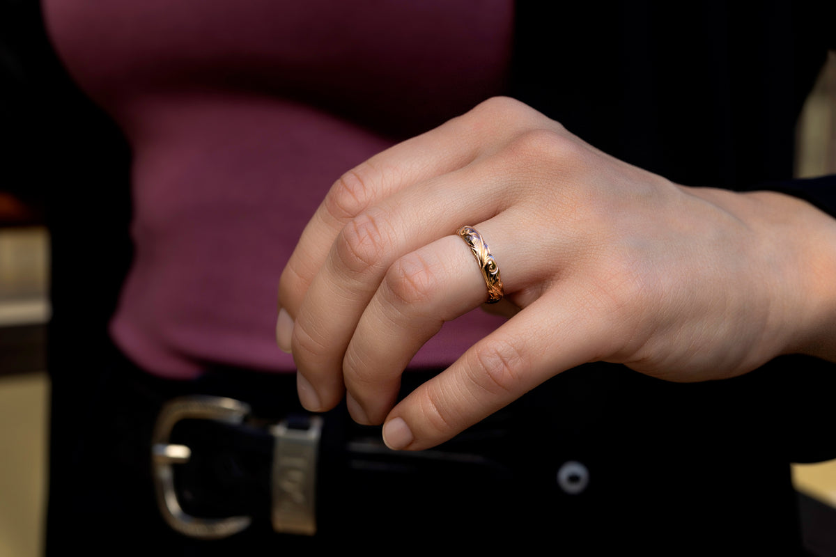 Hand wearing a 4mm gold Hawaiian hand engraved wedding band