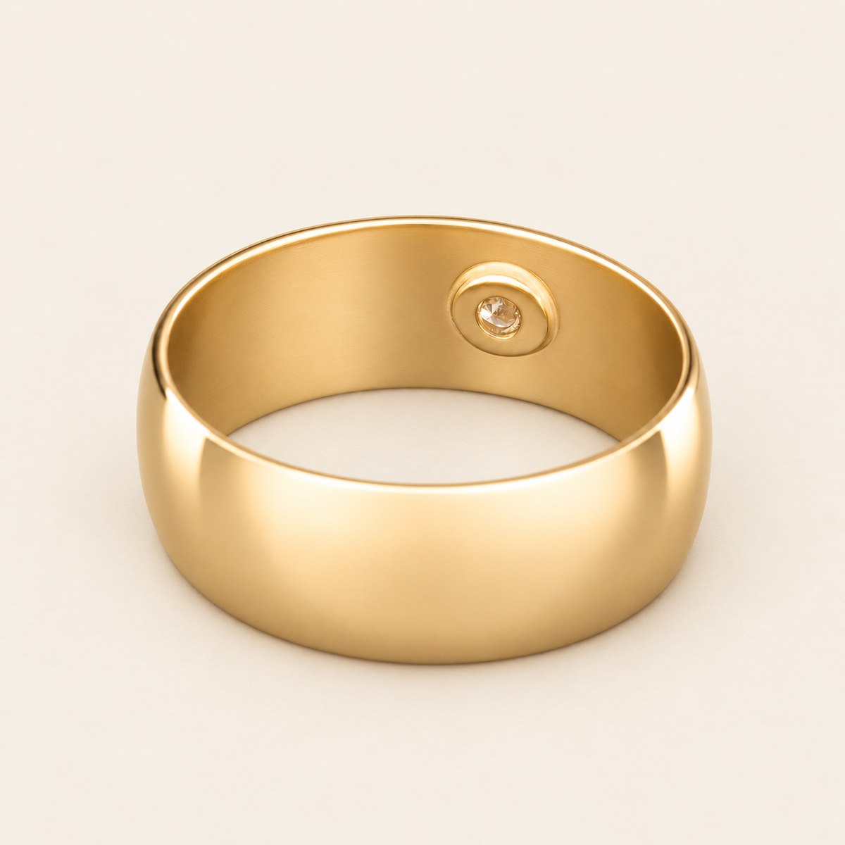 Yellow gold ring showing the interior protective diamond backing, rear view on ivory