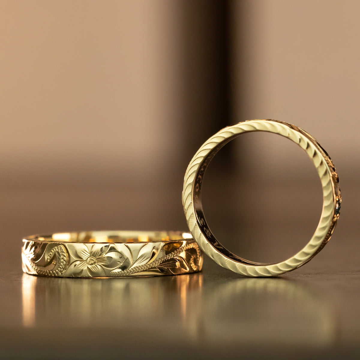 4mm gold hand engraved rings with diamond cut edges, one lying flat and one upright
