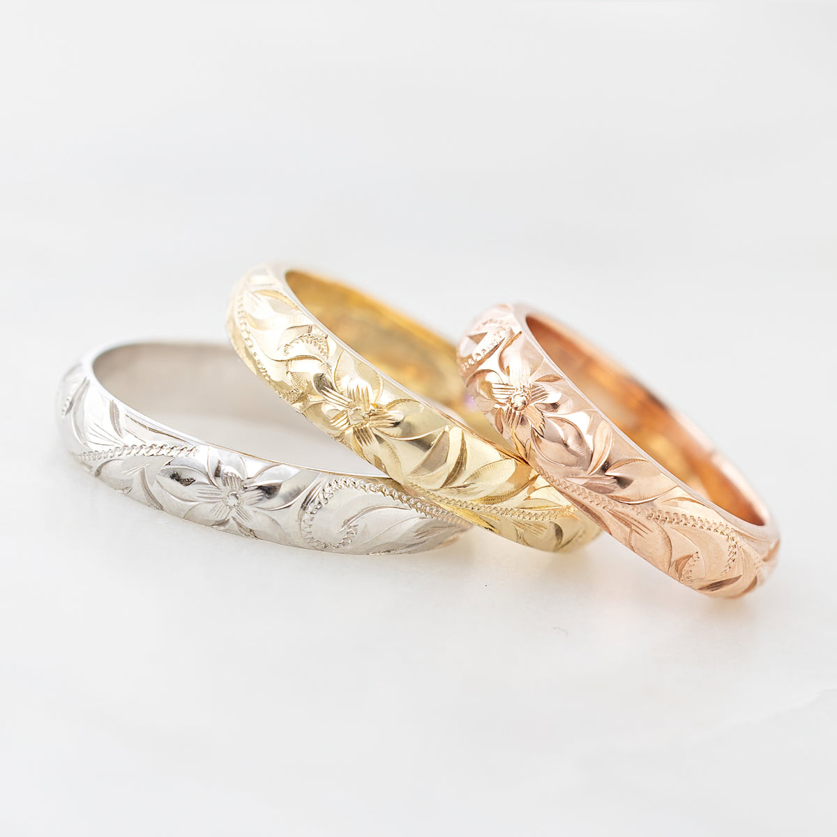 Three 4mm solid gold Hawaiian heritage rings stacked on a white background