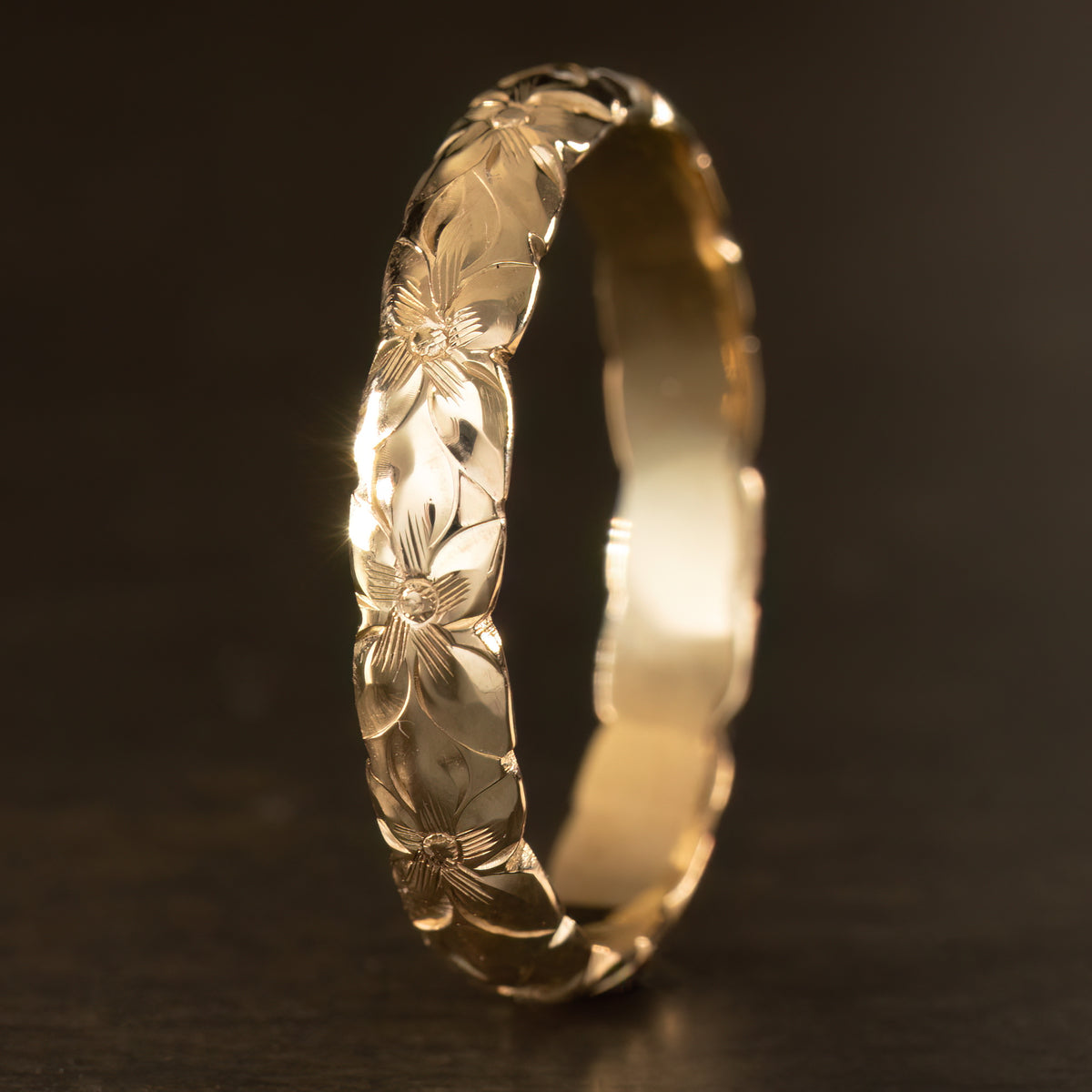 4mm yellow gold ring hand engraved with plumeria flowers around the full band