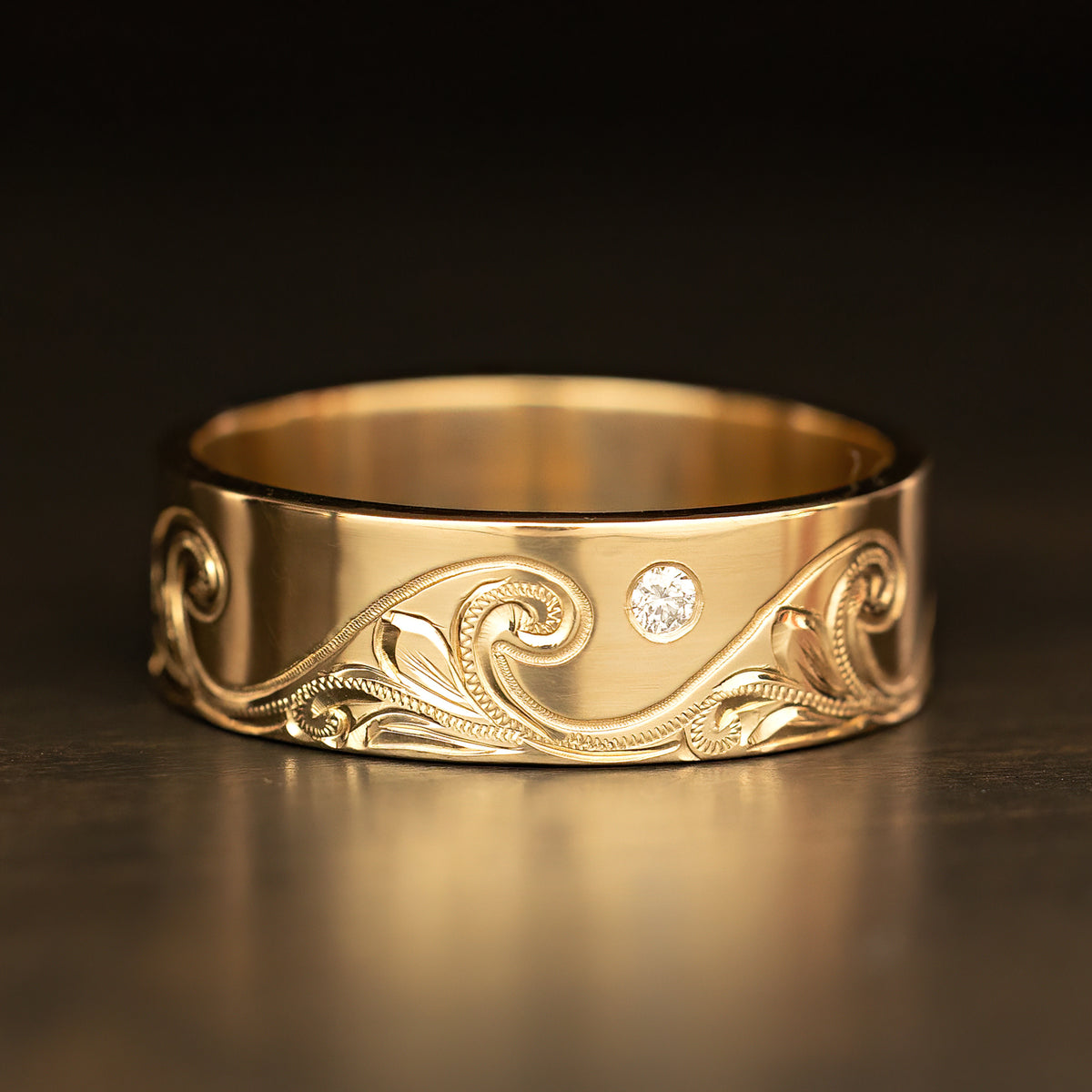 Catch the Wave 8mm gold ring with a single bezel set diamond in the engraved wave