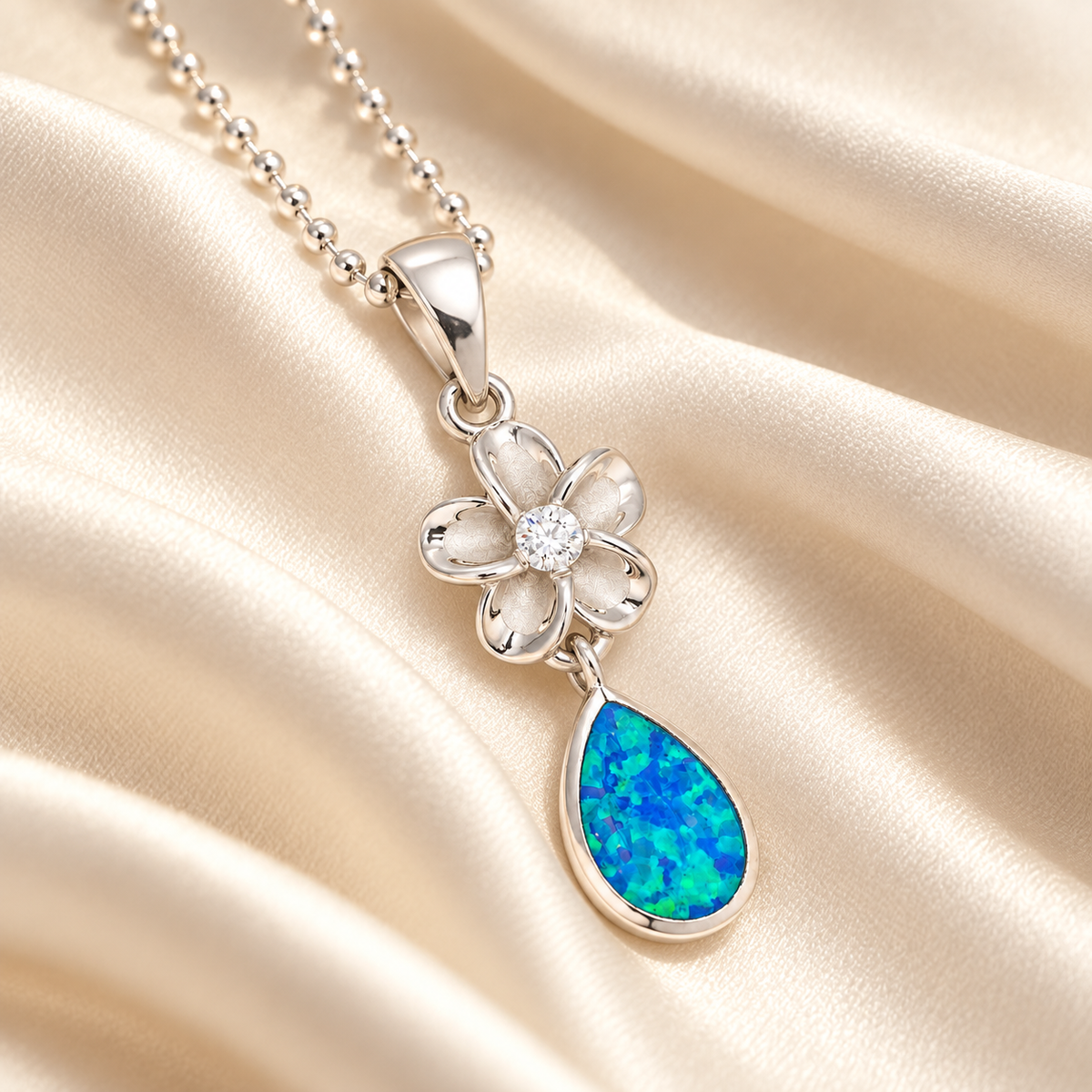 Sterling silver plumeria teardrop pendant with blue opal on ivory silk