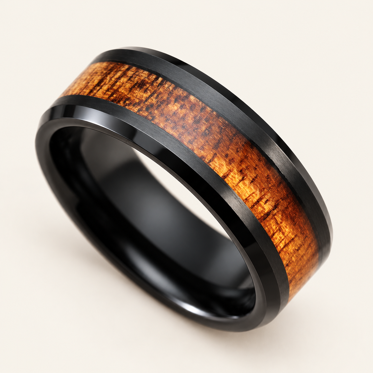 Black tungsten carbide ring with Hawaiian koa wood inlay and beveled edges, primary angled view on ivory