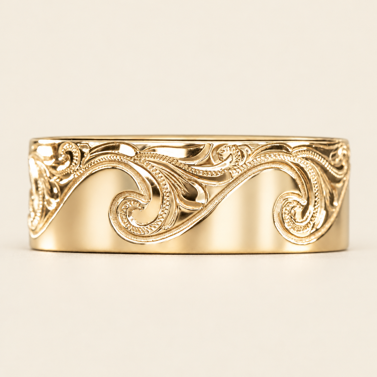 Yellow gold Catch the Wave ring with detailed Hawaiian wave engraving, front view on ivory