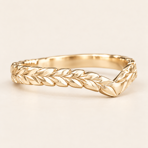 Gold 3mm chevron ring with hand-engraved Hawaiian maile leaves, angled view on an ivory background