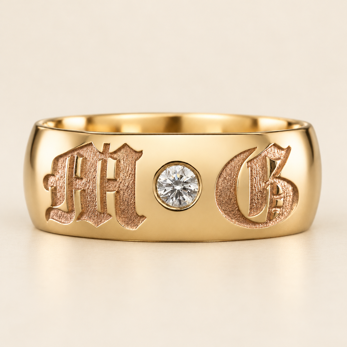 Yellow gold ring with textured Old English initials and a round diamond, front view on ivory