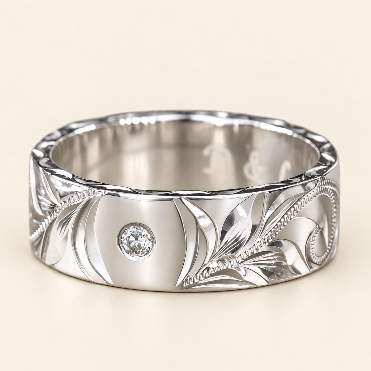 White gold flat heritage ring with one round flush-set diamond, front view showing hand-engraved leaves and scrolls on ivory