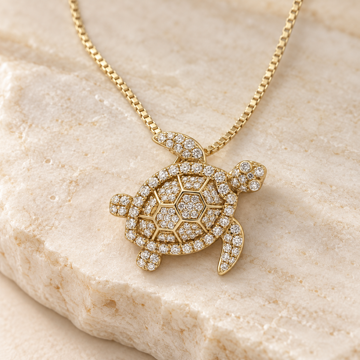 14K yellow gold diamond sea turtle pendant on chain against ivory stone