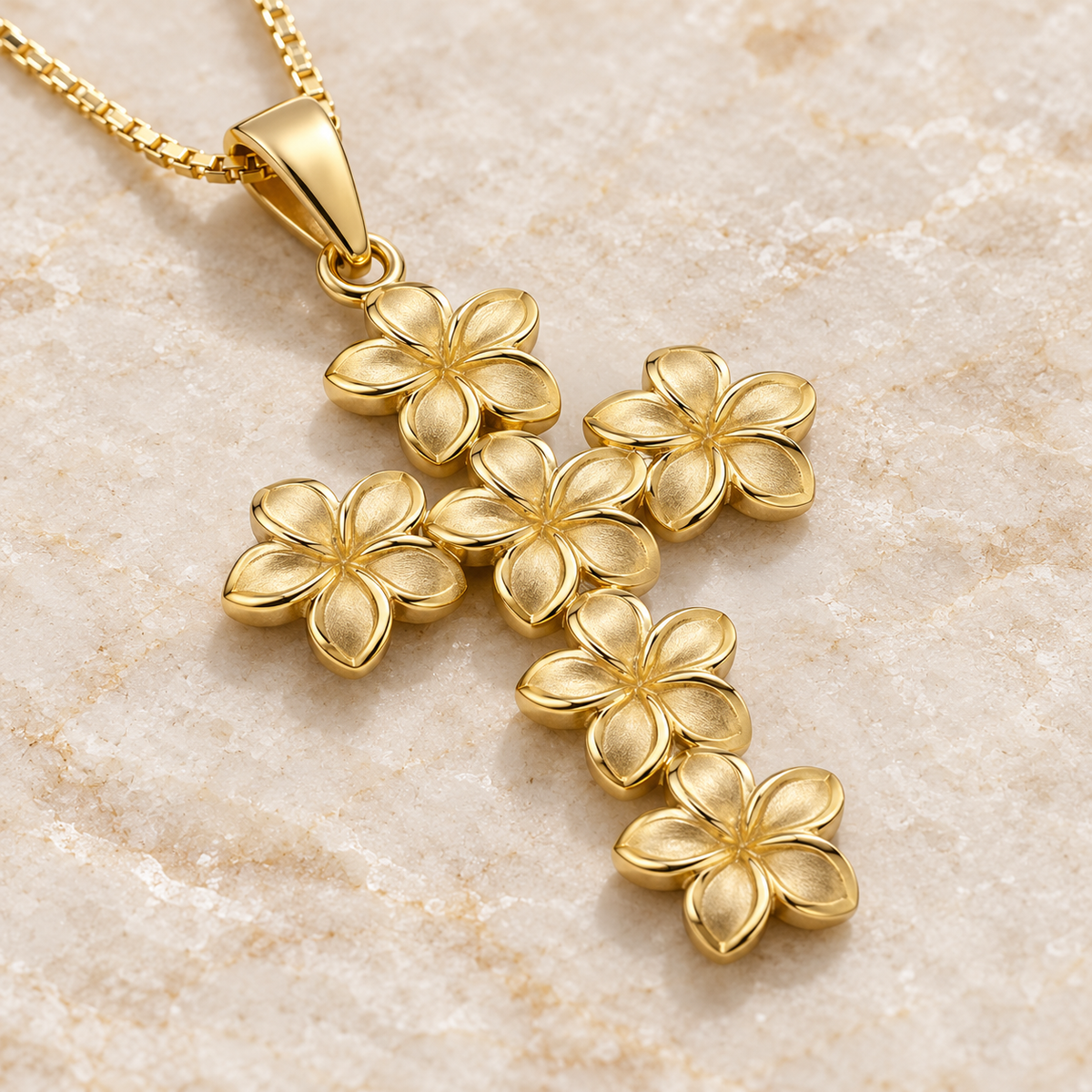 Angled view of 14K gold six-plumeria cross pendant on ivory stone