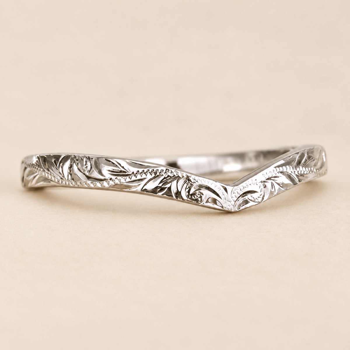 2mm Hawaiian hand-engraved chevron wishbone ring with leaf and scroll details on a warm ivory background