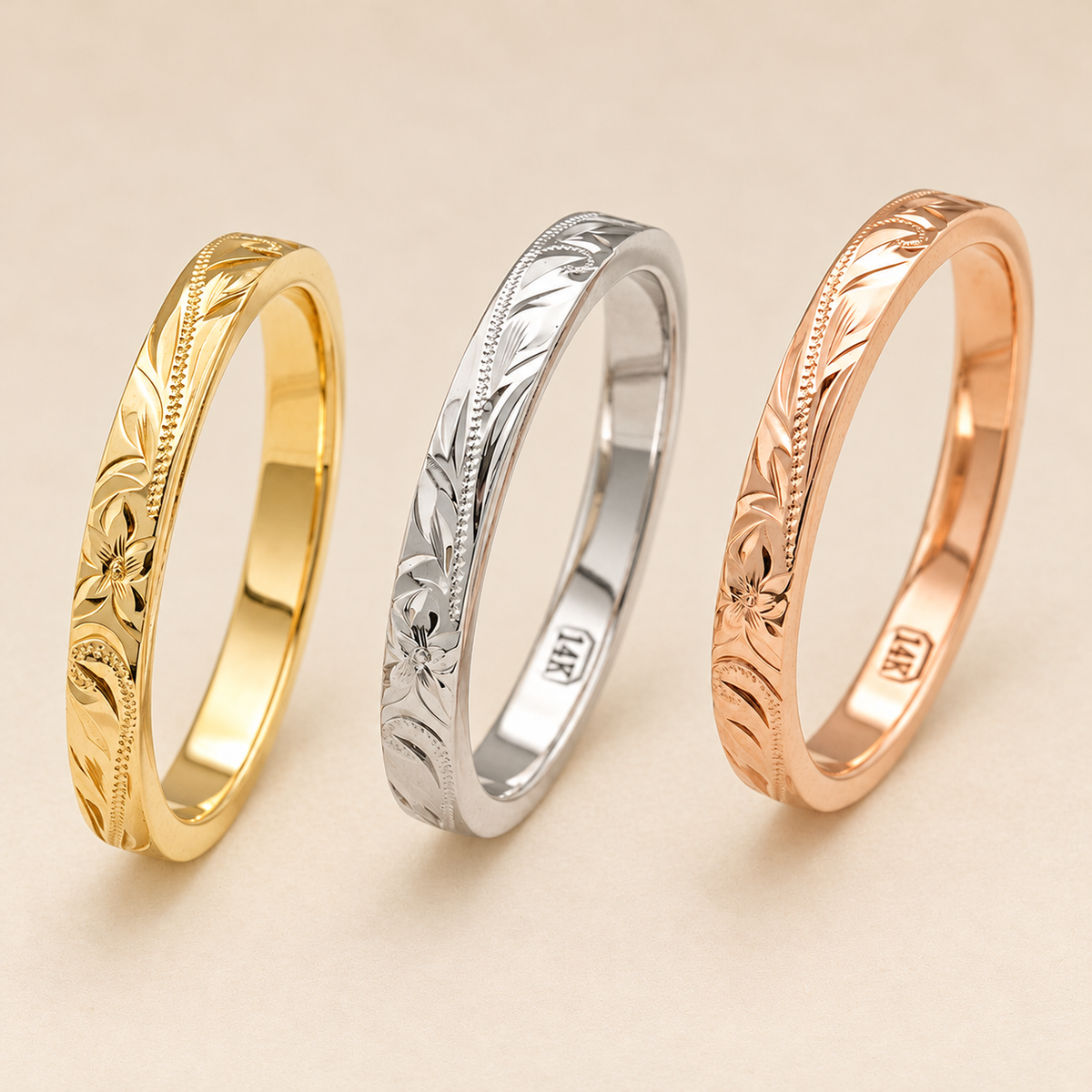 Alternate view of 2.5mm flat Hawaiian rings with plumeria and scroll engraving in yellow, white and rose gold on ivory.