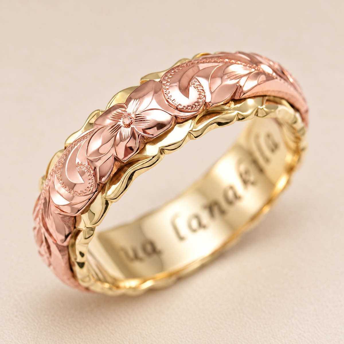Rose and yellow gold Hawaiian heritage ring with floral engraving and scalloped edges on an ivory background.