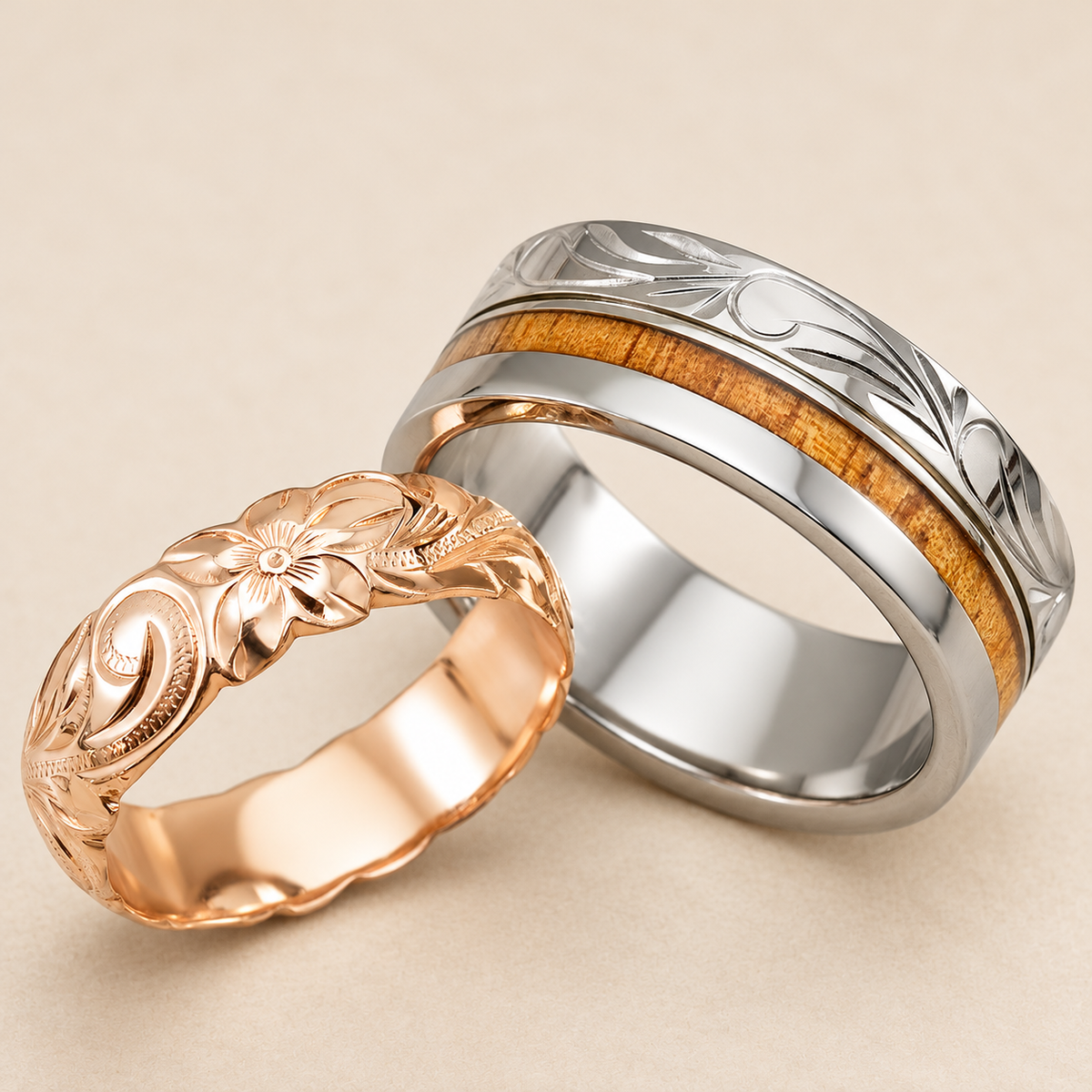 Rose gold Hawaiian floral ring paired with a titanium ring featuring honey-colored koa wood and engraved scrolls on ivory.