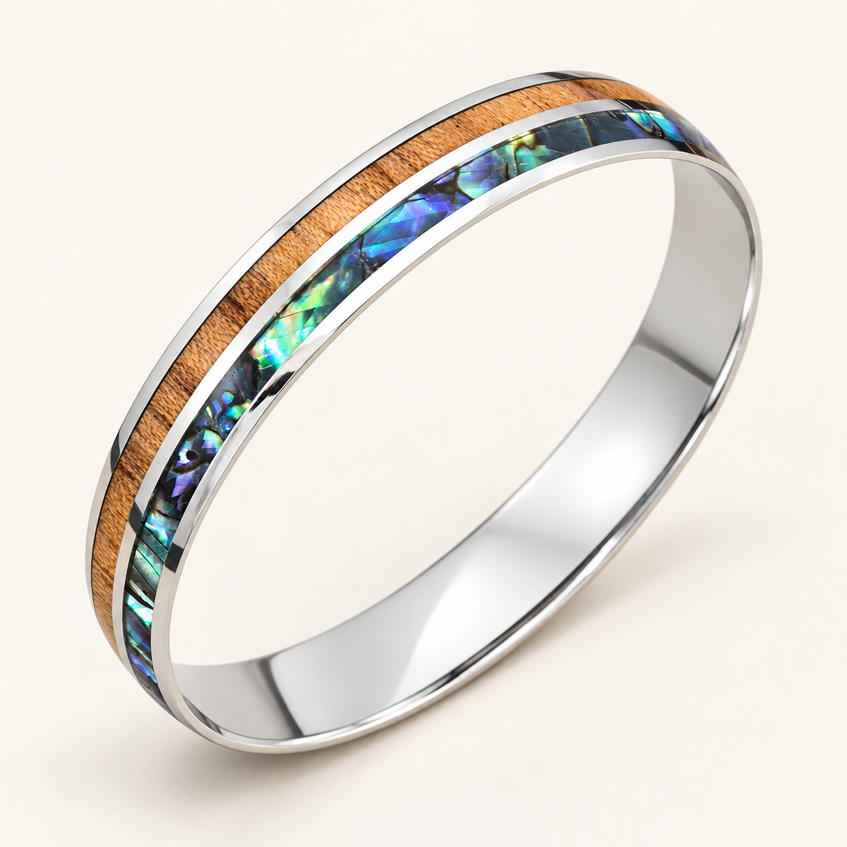 Polished stainless steel bangle with Hawaiian koa wood and abalone paua shell inlays on an ivory background