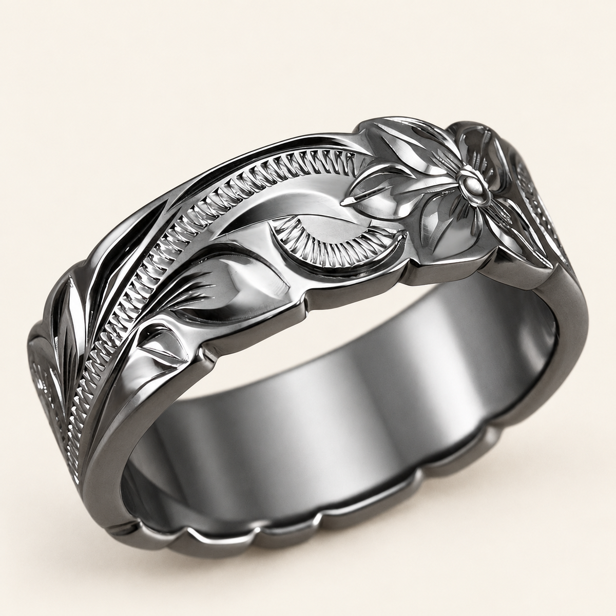 Black rhodium sterling silver 8mm ring with Hawaiian Old English flower and scroll engraving and wave edges, angled view on ivory.