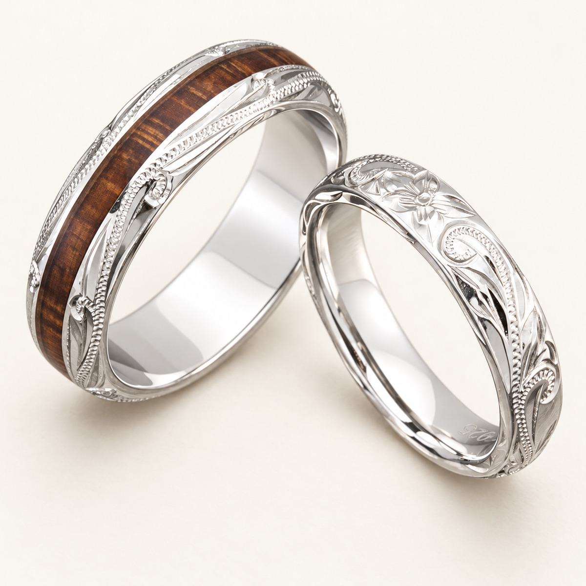 4 mm and 6 mm sterling silver Hawaiian ring pair with floral scroll engraving, one ring with koa wood inlay, on a warm ivory background