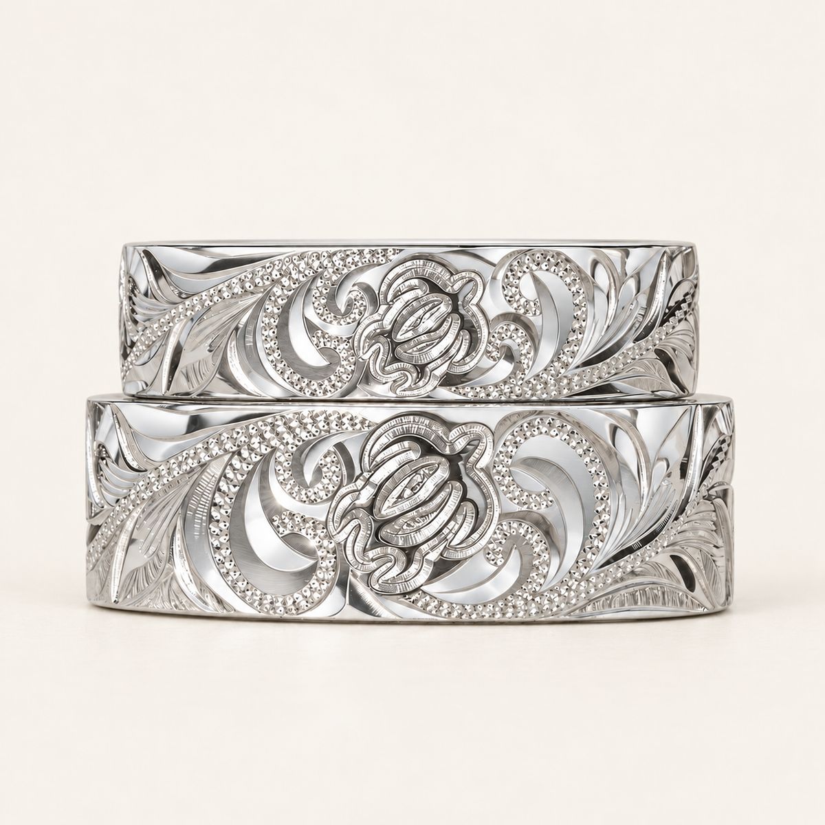 Stacked sterling silver Hawaiian honu rings in 6 mm and 8 mm widths with engraved turtle and scroll designs on ivory