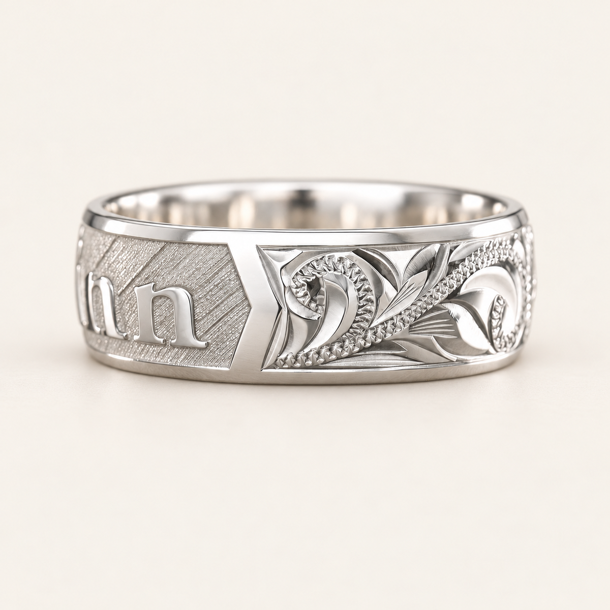 Side view of a sterling silver personalized name ring showing Hawaiian scroll and leaf engraving beside the textured name panel.