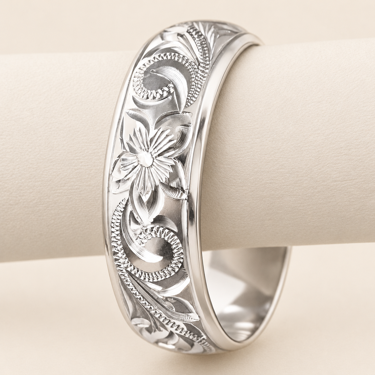 Sterling silver Old English engraved ring with polished edges, upright flower view on an ivory display support