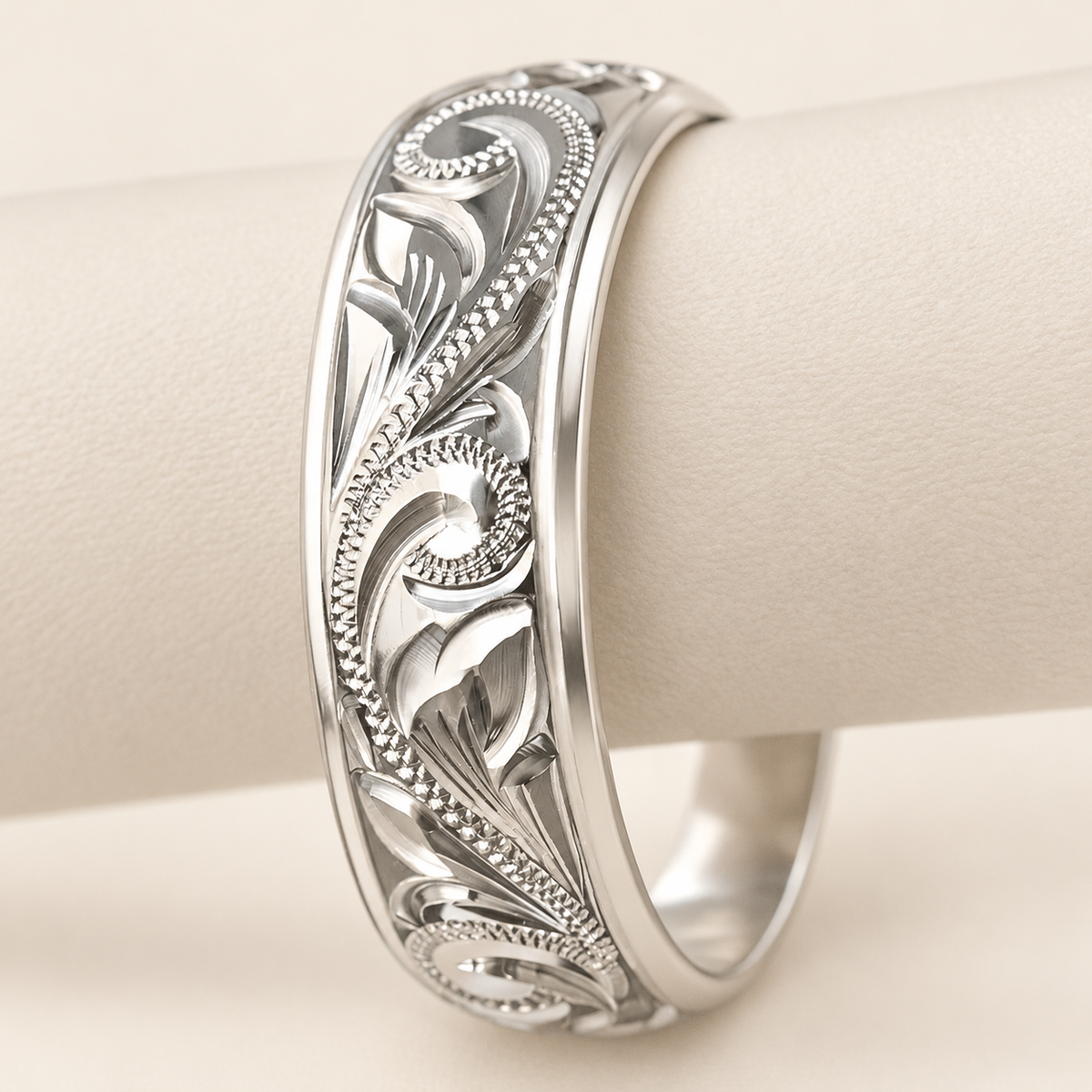 Sterling silver Old English engraved ring with polished edges, upright scroll and leaf view on an ivory display support