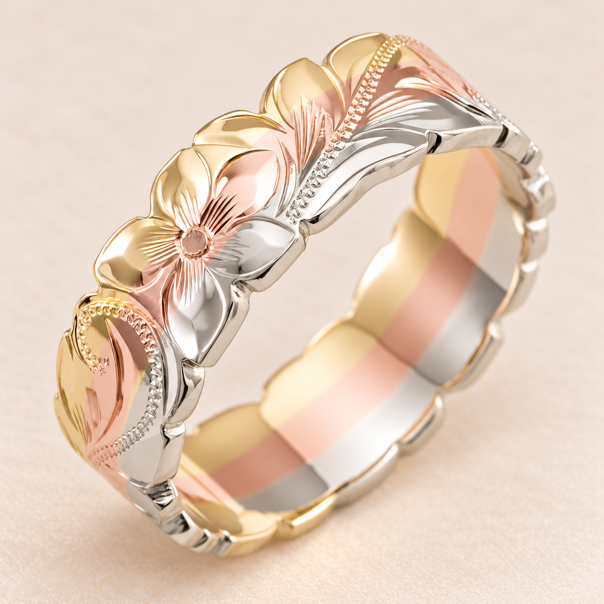 6mm flat tri-gold Hawaiian ring with yellow, rose and white gold bands, floral scroll engraving and scalloped wave edges on ivory.